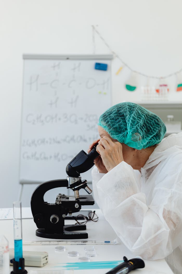 pexels-photo-8539517 Researcher in protective gear using a microscope in a laboratory setting for chemical analysis.